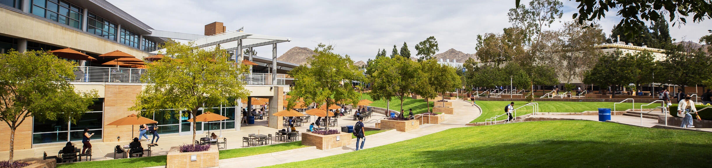 A view of the Highlander Union Building (HUB) Plaza. The HUB building and green grass lawns frame the setting.