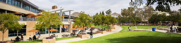 A view of the Highlander Union Building (HUB) Plaza. The HUB building and green grass lawns frame the setting.